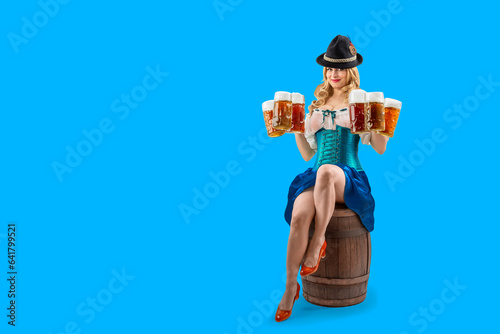 Oktoberfest girl waitress sitting on a wooden barrel. Woman in dirndl, tyrolean hat serving big beer mugs. Isolated background. Traditional Bavarian, German, Austrian party, autumn festival.