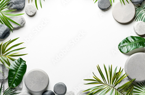 Fotografia A minimalist and zen-like aesthetic white background with a border of grey stones and green tropical and palm tree leaves