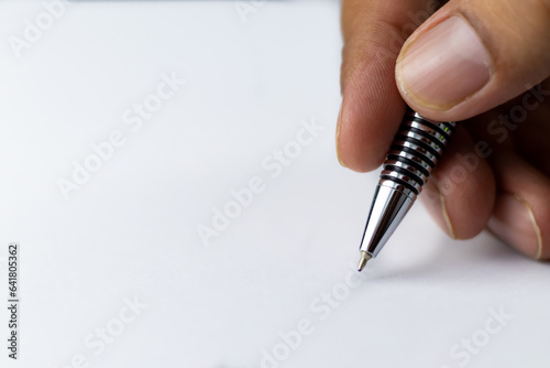 Close up shot of a hand holding ball pen and writing on blank paper with no text on it and copy space -Education and Start concept.
