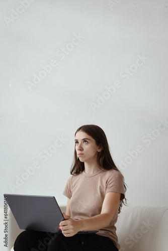 Young woman is sitting on a sofa with a laptop. Concept online session with a psychologist
