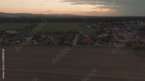 Beautiful drone shot of a small town during a dawn with the sun already behind the horizon, sunset view of a lovely village with dramatic sky in the background.