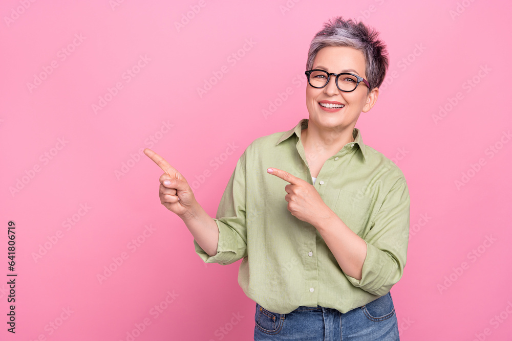 Portrait of positive friendly agent lady toothy smile indicate fingers empty space isolated on pink color background