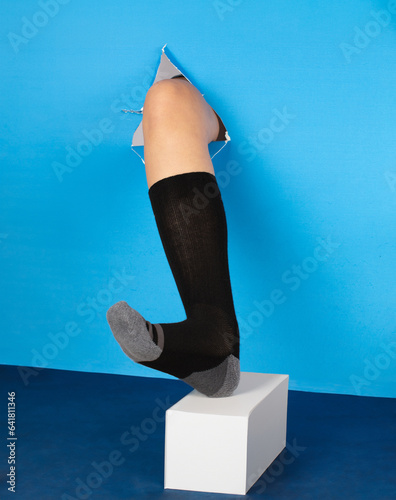 leg punctured through wall, product photography on a blue background socks