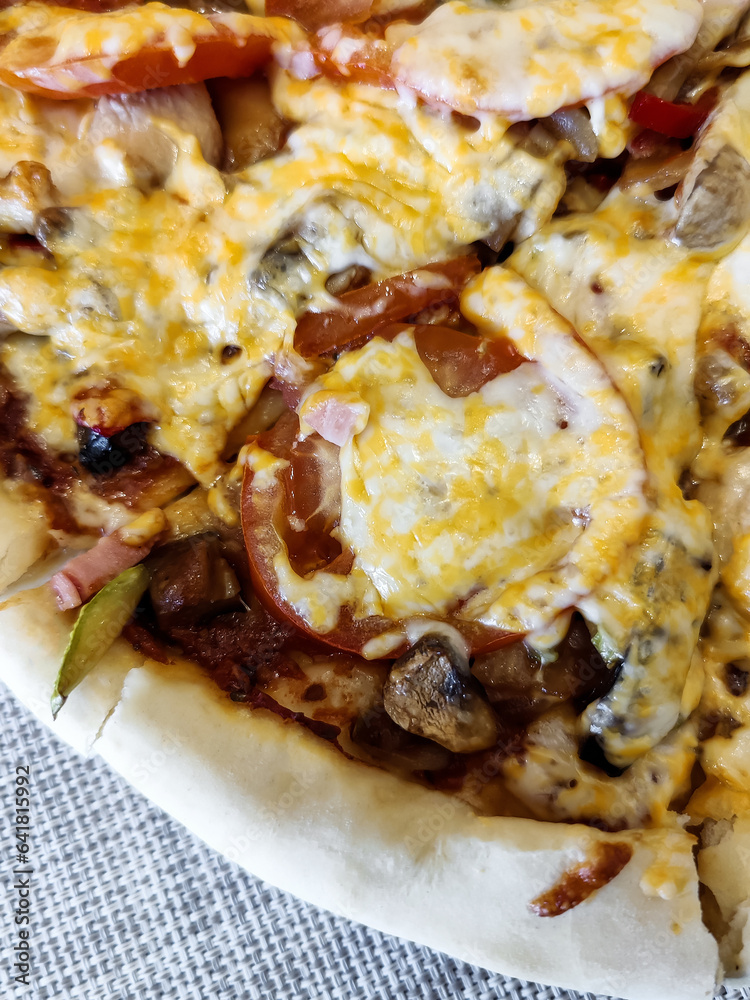 Delicious sliced grilled homemade pizza with eggplant, zucchini, tomatoes, olives, chicken meat, mushrooms and filled with cheese. Close-up. Selective focus. Delicious sliced grilled homemade pizza with eggplant, zucchini, tomatoes, olives, chicken meat, mushrooms and filled with cheese. Close-up. Selective focus.