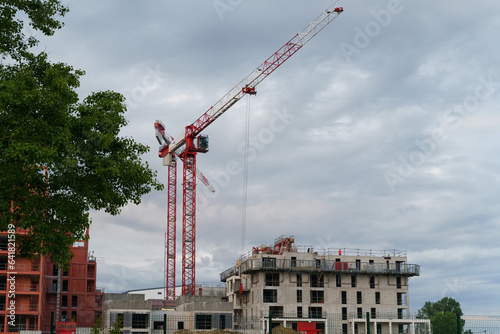 The construction of a residential building, workers are working on a building under construction, nearby cranes are lifting loads