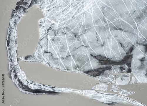 Frozen and cracked ice on water surface in daylight