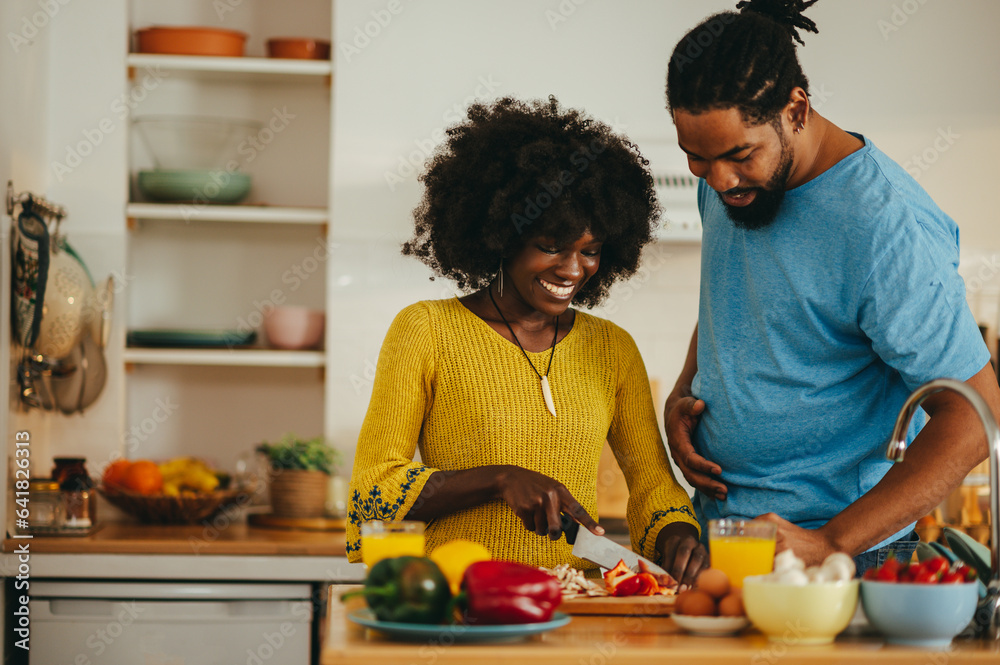 A happy multicultural couple is cooking dinner together at home.