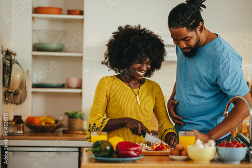 Fotografie A happy multicultural couple is cooking dinner together at home.