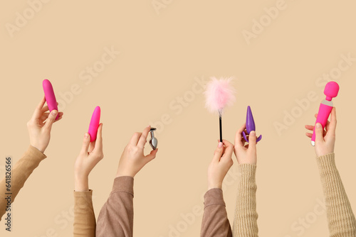 Women with sex toys on beige background