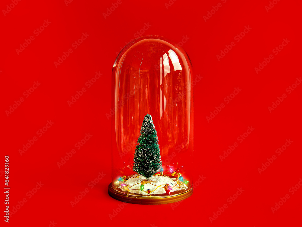 Christmas composition. Snow globe with Christmas tree and lights on red table background. Flat lay, top view, copy space. New Year card. Merry Christmas. Glass bell, snow globe, mock-up, template.