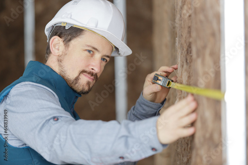 confident worker measuring plaster wall