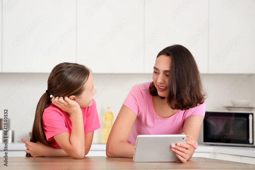 Mother and daughter using tablet computer in kitchen at home Mother and daughter using tablet computer in kitchen at home