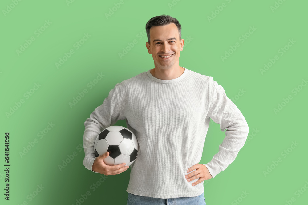 Young man with soccer ball on green background