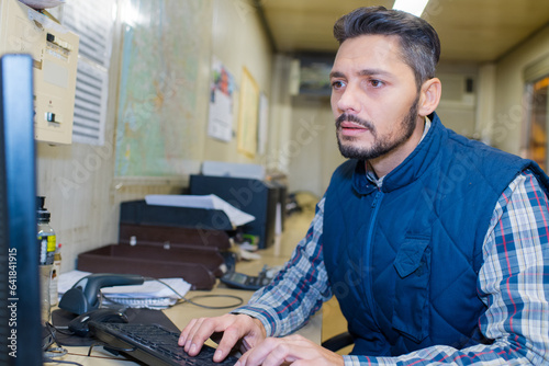 man at computer in on-site warehouse office photo