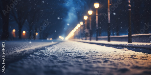 Snowy winter road at night with street lamps and falling snow.