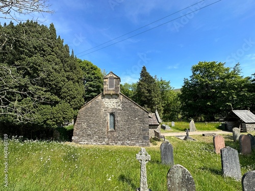 Side view of, St Leonard's Church, Chapel-Le-Dale, with long grasses, wild plants, gravestones, and old trees in, Chapel le Dale, UK photo