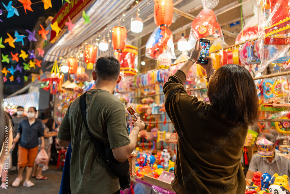 People in front of traditional colorful lanterns hanging on a stand in the streets of Cholon in Ho Chi Minh City, Vietnam during Mid Autumn Festival. Joyful and happy.