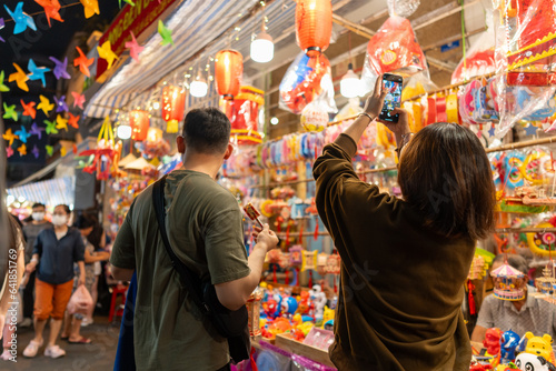 People in front of traditional colorful lanterns hanging on a stand in the streets of Cholon in Ho Chi Minh City, Vietnam during Mid Autumn Festival. Joyful and happy.