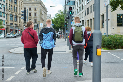 Group of people are crossing city road on green light of traffic light