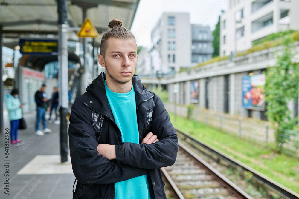 Portrait of young confident guy at railway station of electric city train