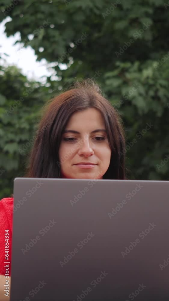 Attractive young woman in red dress using modern laptop, working remotely as freelancer, outdoors on a city street, vertical Attractive young woman in red dress using modern laptop, working remotely as freelancer, outdoors on a city street, vertical