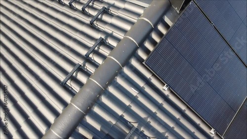 Drone flight over roof with solar panels ending up on electric car charging with solar electricity .