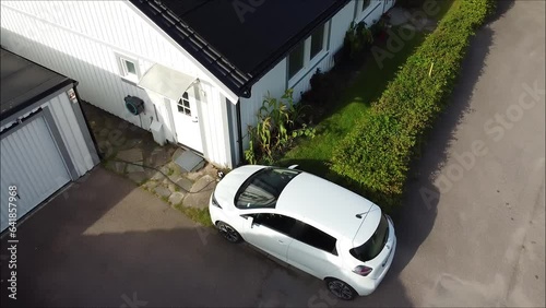 Slow drone flight over electric car charging with solar electricity from solar panels.