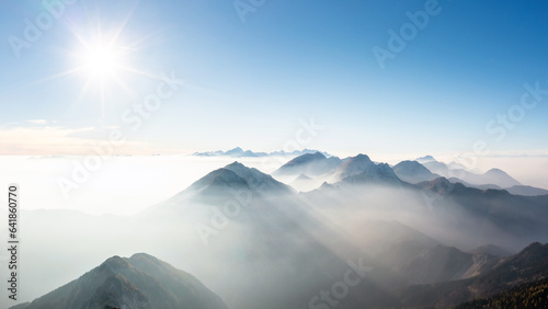 Astonishing scene of mountain range horizon in the morning mist, illuminated by the light of the rising sun, aerial shot. The majestic beauty of nature concept.