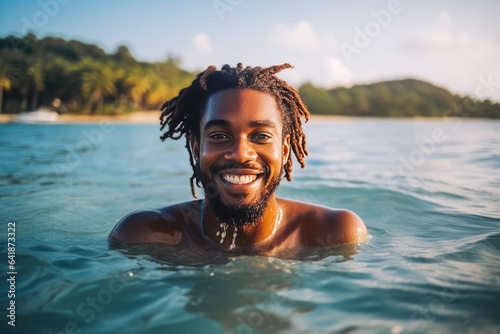 Portrait of handsome young african american man smiling and having fun while swimming in the ocean