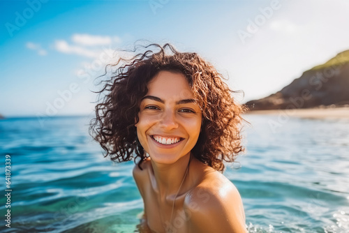 Portrait of beautiful young caucasian woman smiling and having fun while swimming in ocean