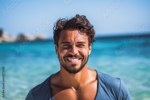 Portrait of handsome young caucasian man smiling and having fun while standing by the ocean