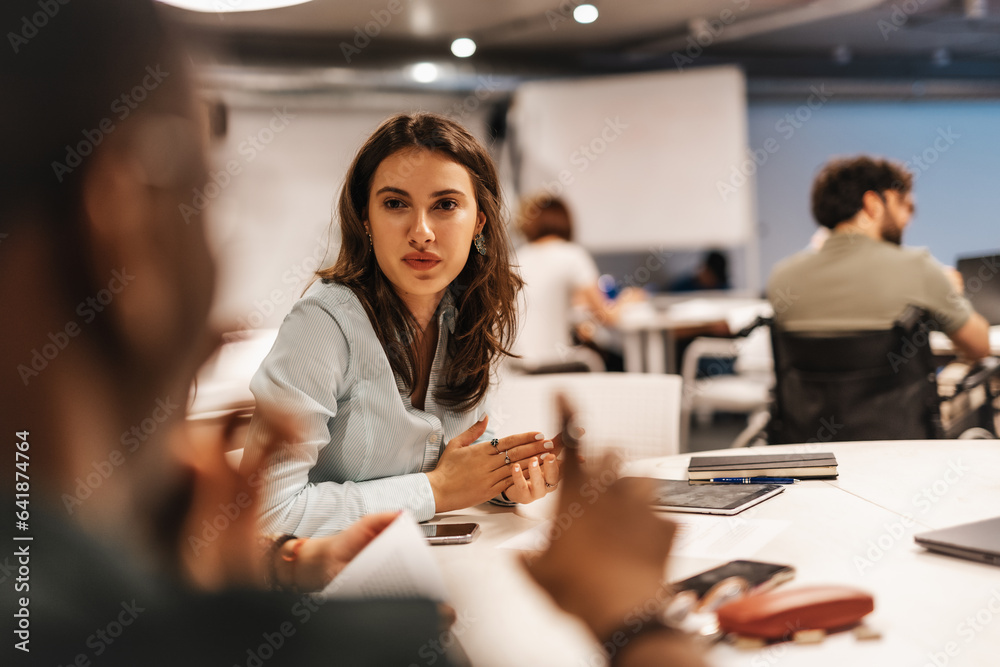 Female employee listening to her male colleague explaining something.