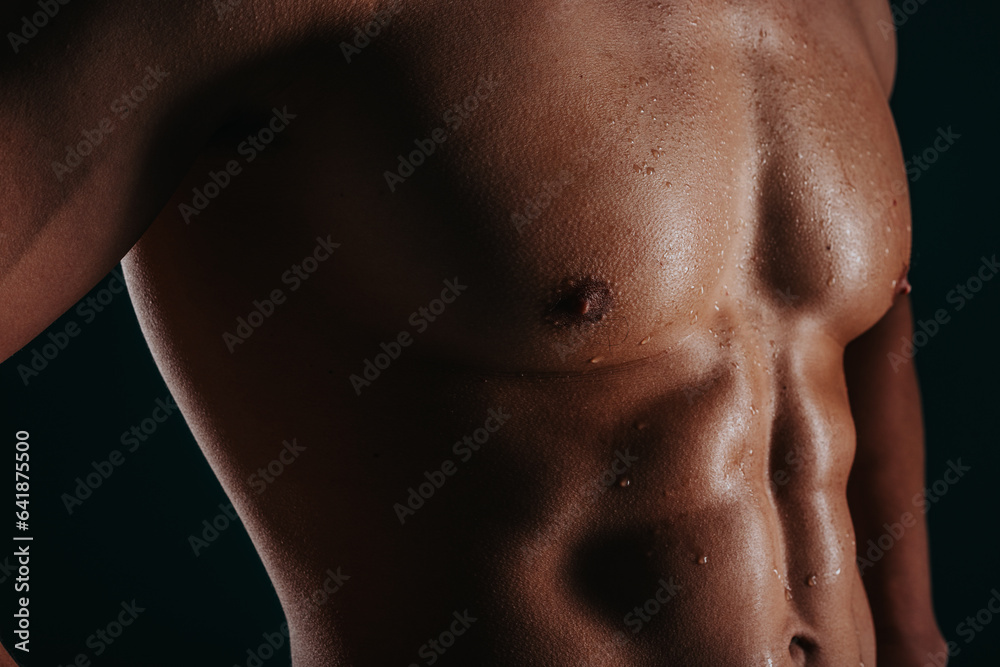 Cropped image of sweaty bodybuilder. Male bodybuilder showing his six pack abs, close up shot. Cropped image of sweaty bodybuilder. Male bodybuilder showing his six pack abs, close up shot.