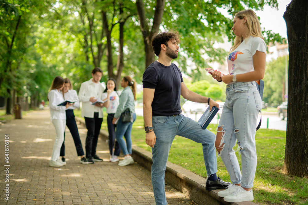 College couple discussing subject before exam standing on a sidewalk College couple discussing subject before exam standing on a sidewalk