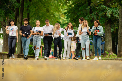 Big group of students. Large group of university students. College students walking. Students walking one next to each other. Students discussing while walking outdoors.