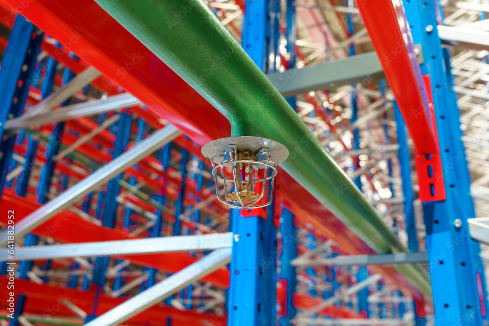 Fire sprinkler in a large warehouse with metal shelving
