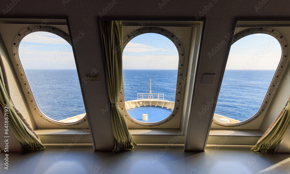 Windows looking out to bow of cruise ship and blue open ocean