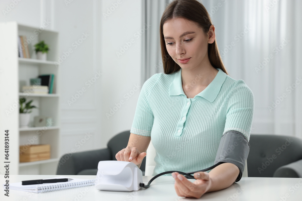 Woman measuring blood pressure with tonometer at home Woman measuring blood pressure with tonometer at home