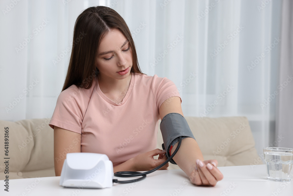 Woman measuring blood pressure with tonometer at home Woman measuring blood pressure with tonometer at home