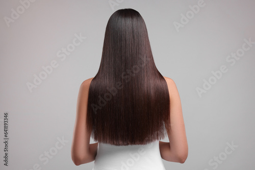Woman with healthy hair after treatment on light gray background, back view