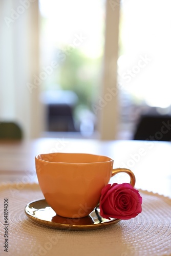 Cup of hot drink and red rose on table indoors. Space for text