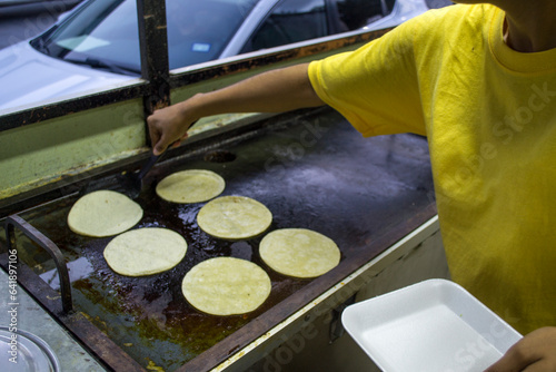 Cocinera calentando tortillas de maíz en un comal caliente. carrito de comida rápida callejera en México.