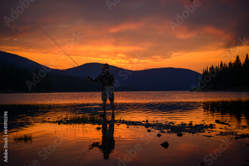 Man fly fishing in a Montana lake at sunset.