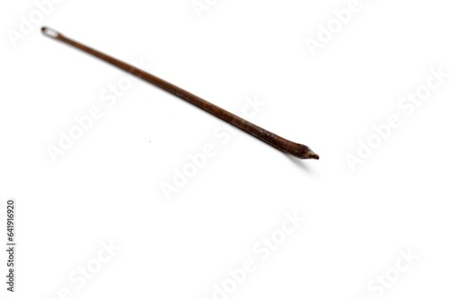 This mattress thread needle made of metal looks rusty and was photographed on the isolated white background