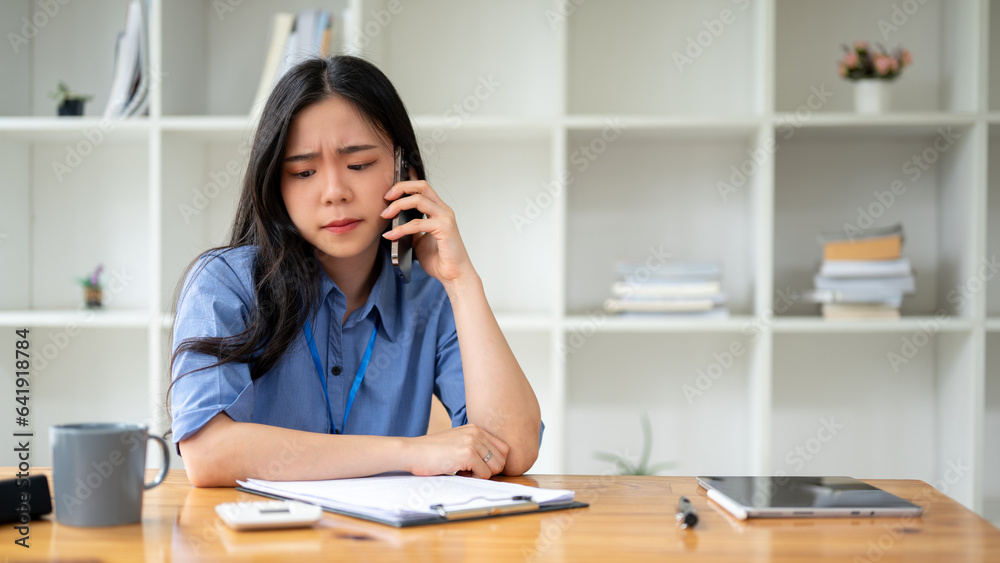 A stressed Asian businesswoman is having a serious conversation over the phone A stressed Asian businesswoman is having a serious conversation over the phone