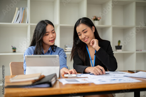 A professional Asian female accountant is helping and explaining financial work to her colleague