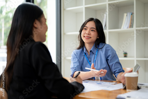 A businesswoman is talking and explaining financial profit to a female client in the office.