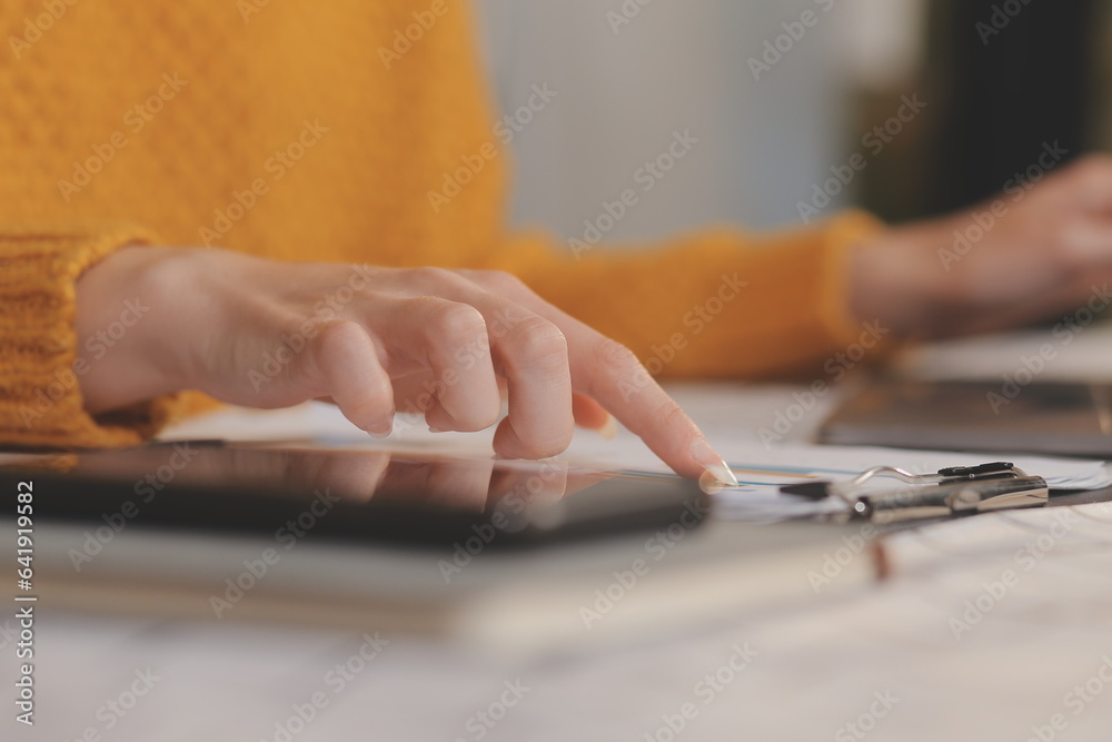 Cropped photo of Freelancer business Asian woman holding coffee cup and at doing planning analyzing the financial report, business plan investment, finance analysis the workplace. Cropped photo of Freelancer business Asian woman holding coffee cup and at doing planning analyzing the financial report, business plan investment, finance analysis the workplace.