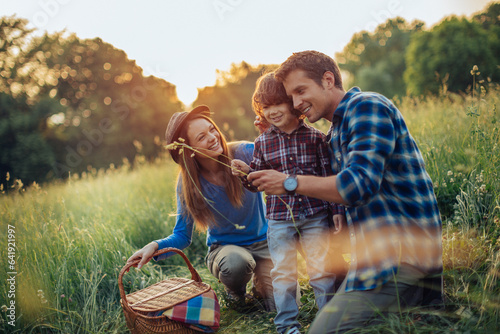 Tableau sur toile Young caucasian family having a picnic on a grassy field in nature