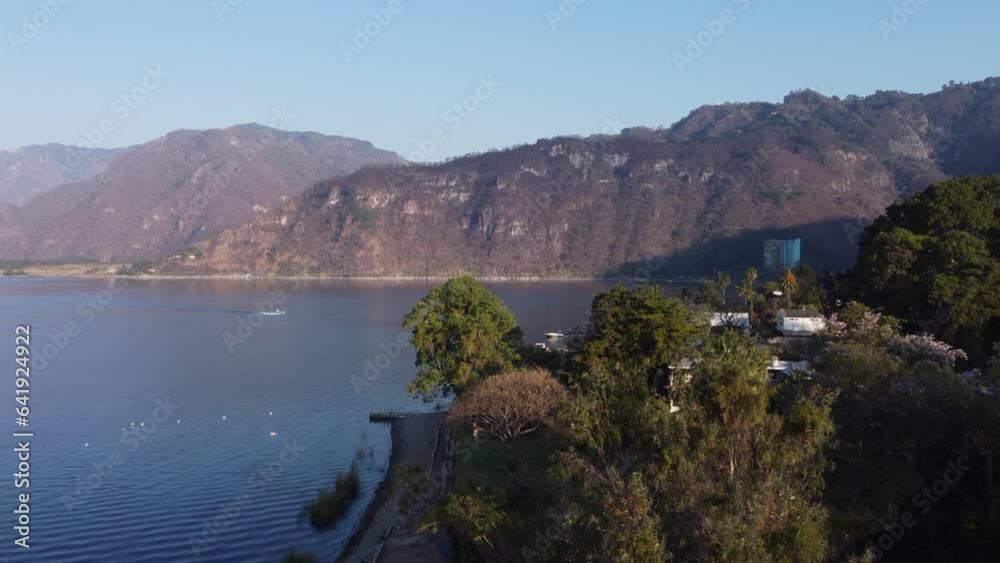 Aerial rises over blooming tree to reveal Lake Atitlan bay, Guatemala Aerial rises over blooming tree to reveal Lake Atitlan bay, Guatemala